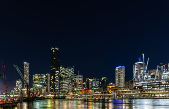 Brisbane city skyline at night along the Brisbane River with one building illuminated to read "BNE 2032" to announce Brisbane as the host of the 2032 Summer Olympic Games.