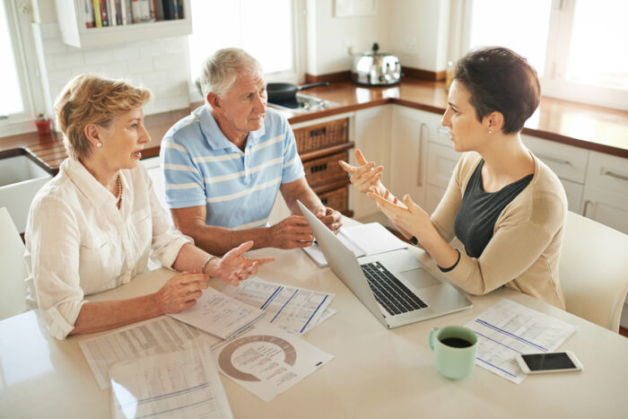 Expert talking to retired couple about buying wisely in the property market. 