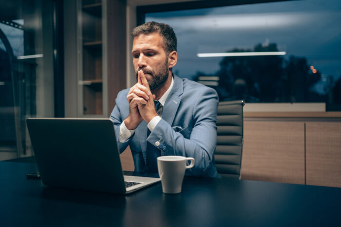 Shot of businessman working with laptop at office during night. Overworked businessman staying late hours in the office and using laptop.