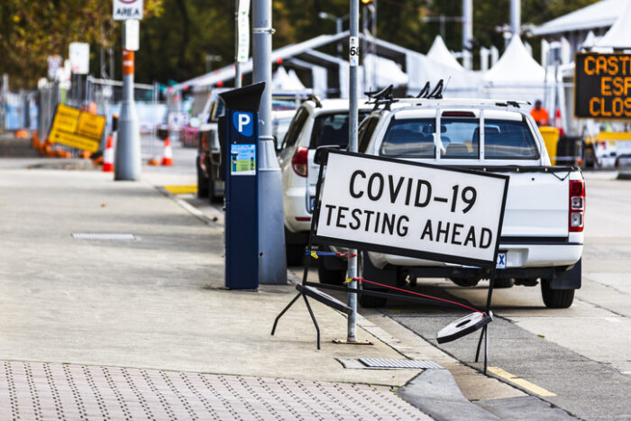 Sign Of COVID-19 Testing Ahead on the street in Hobart - Tasmania, with a COVID Clinic on the background