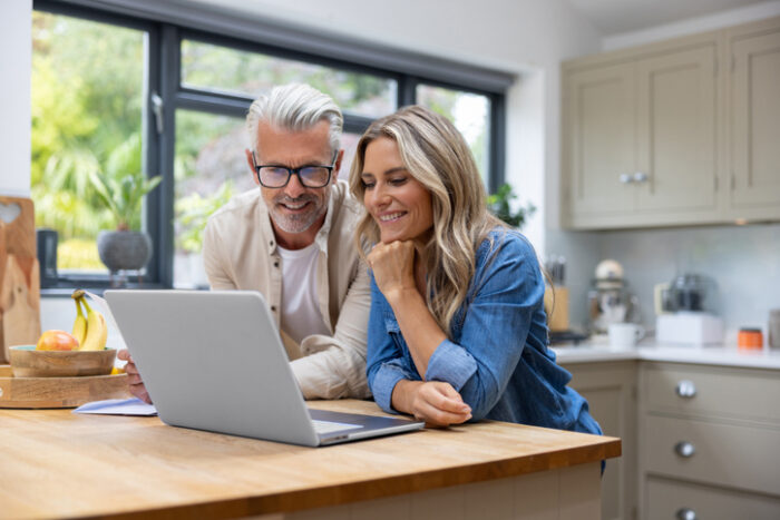 Retirees looking at tax rate on a trust on their laptop in a bright kitchen