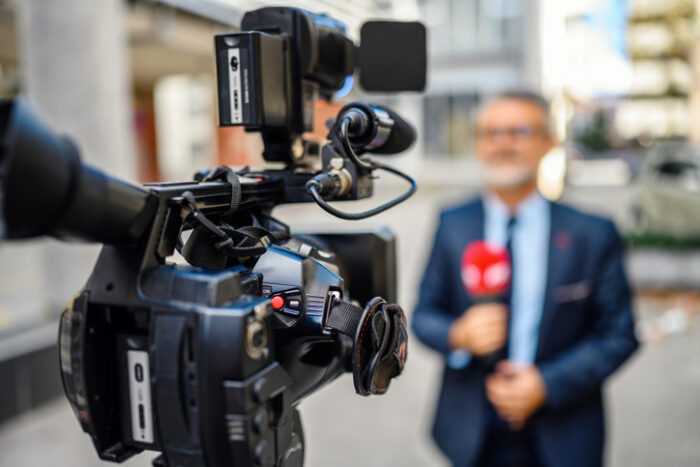 media discussing interest rate drops in australia in front of camera, in relation to 2025 property market predictions.