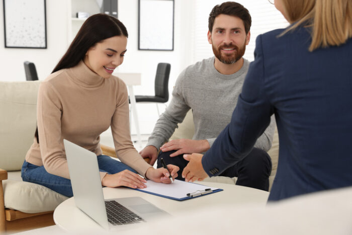 Couple signing contract in real estate agent's office after understanding capital improved value vs market value