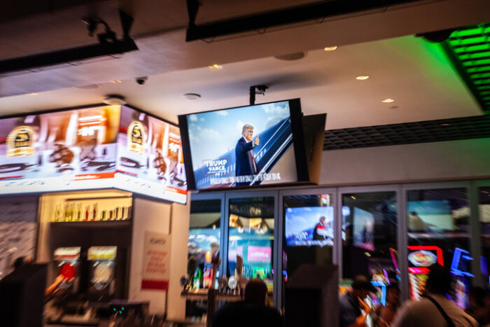 Las Vegas - August 19, 2024: This image features a TV commercial for Donald Trump's 2024 US presidential campaign, seen in a bar setting in Las Vegas. The speed blur of the screen and surrounding neon lights create a sense of fast-paced energy, typical of the lively atmosphere found in the city. This photo is ideal for political, commercial, or nightlife-themed uses.