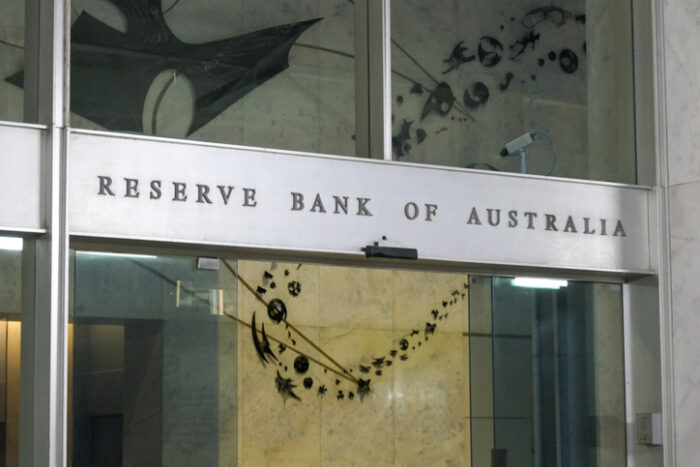 The main pedestrian entrance of the Reserve Bank of Australia building at 65 Martin Place in the central business district (CBD) of Sydney. The automatic glass doors are briefly open. Three armed guards (not shown here) guard the foyer. This image was taken from outside the building in Martin Place, looking through the glass facade, on an overcast afternoon on 18 February 2025