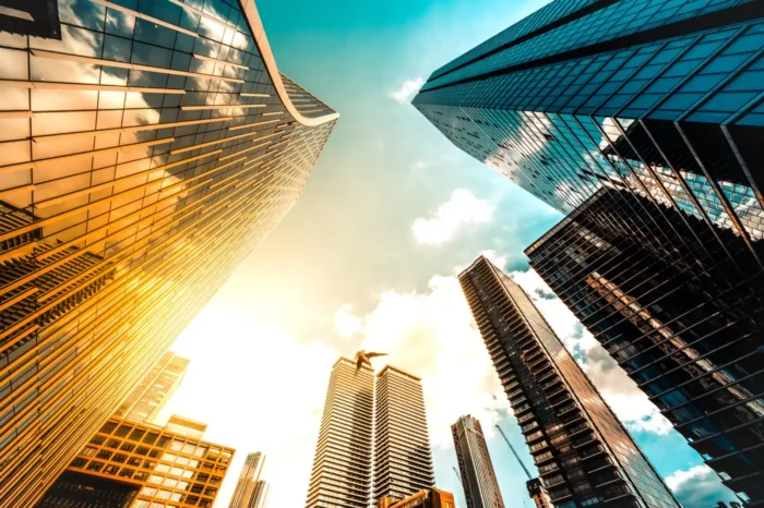 Shot of commercial buildings from the ground looking up at the office building faces with bright orange and blue sky.