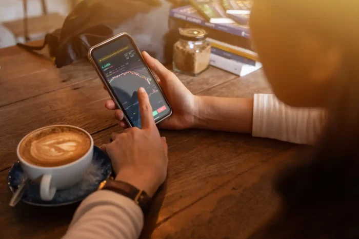 Person with phone in their hand buying shares in Australia. 