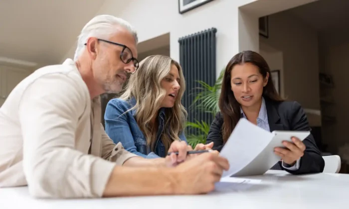 Mature investors with financial advisor at a table with documents. 